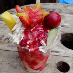 Vaso de frutas, cubiertas con crema, sirop y queso.